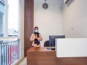 una persona con una maschera facciale in ufficio di Super OYO 90115 Near Pasar Baru a Giacarta