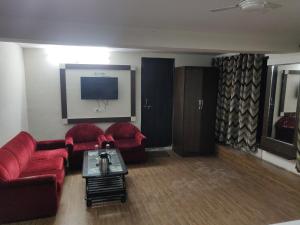 a living room with two red couches and a tv at Hotel Vaidehi in Udaipur
