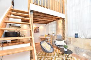 a loft apartment with a staircase and two chairs at CMG Ile Saint Louis in Paris