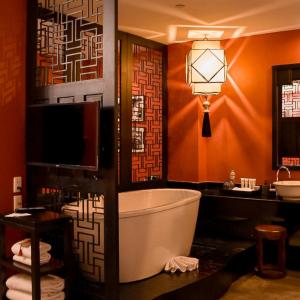 a bathroom with a tub and a tv and a sink at Shanghai Mansion Bangkok - SHA Extra Plus in Bangkok