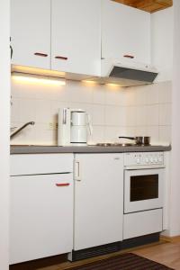 a kitchen with white cabinets and a stove top oven at Ferienwohnung am Hauchen in Reit im Winkl