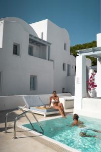a woman standing in front of a swimming pool at Palmariva Villas in Fira
