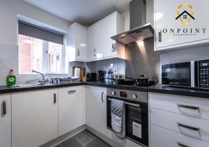 uma cozinha com armários brancos e um forno com placa de fogão em OnPoint - Spacious 2 Bed Apt - FREE Parking em Reading