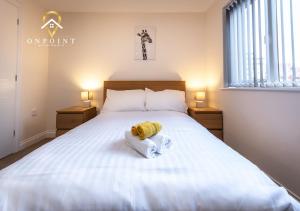 a bedroom with a bed with a yellow towel on it at OnPoint - Spacious 2 Bed Apt - FREE Parking in Reading