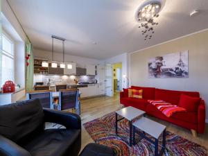 ein Wohnzimmer mit einem roten Sofa und einer Küche in der Unterkunft Residenz am Seeufer in Waren (Müritz)