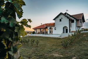 a white house with a field in front of it at Holiday House Belajec in Popovača