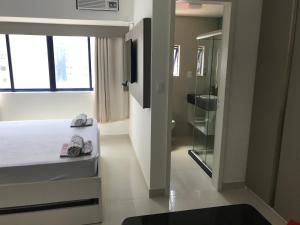a bedroom with a bed and a window and a bathroom at Studio Everest Flats in Recife