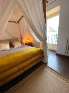 a bedroom with a canopy bed with a window at Kourline Villalunoterie Futuroscope Piscine spa in Oyré