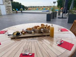a table with a basket of bread and a bottle of orange juice at Kourline Villalunoterie Futuroscope Piscine spa in Oyré