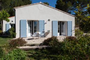 Une petite maison blanche avec volets bleus dans l'établissement Chambre d'hôtes le Mirail, à La Motte-dʼAigues