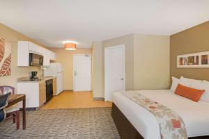 a hotel room with a bed and a kitchen at MainStay Suites Chicago Hoffman Estates in Hoffman Estates