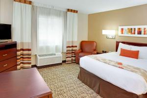 a hotel room with a large bed and a chair at MainStay Suites Detroit Auburn Hills in Auburn Hills
