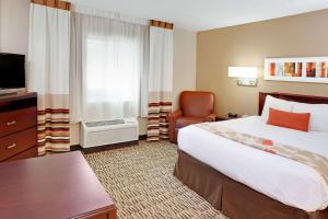 MainStay Suites Detroit Farmington Hills في فارمنجتون هيلز: غرفة فندقية بسرير كبير وكرسي