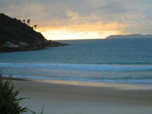 una playa al atardecer con el océano y las palmeras en Morada d'Omar 4 Ilhas, en Bombinhas