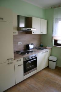 a kitchen with white cabinets and a stove top oven at Gästehäuser Kappelmühle in Grünstadt