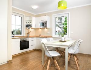 - une cuisine avec des placards blancs, une table et des chaises dans l'établissement Haus LUV, à Poel