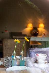 einen Tisch mit zwei Vasen mit gelben Blumen darin in der Unterkunft B&B La Cereza in Oudenaarde