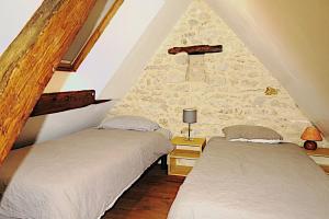 two beds in a room with a stone wall at La Ferme des Acacias in Ormoy-la-Rivière