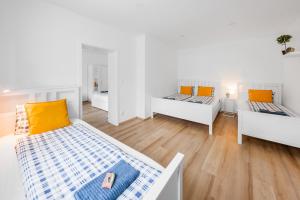 una camera con tre letti con cuscini arancioni e blu di Chalupa Na Dědině a Dolní Dunajovice