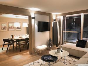 een woonkamer met een bank en een eetkamer bij Luxueux appartement skis aux pieds, jacuzzi privatif in Courchevel
