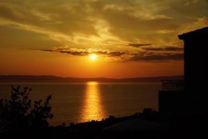 een zonsondergang boven een lichaam van water met de zon bij ORATO VILLAGE in Pyrgos