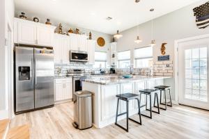 une cuisine avec des armoires blanches et un réfrigérateur en acier inoxydable dans l'établissement Seahorse Beach House, à Galveston