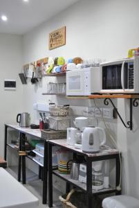 una cocina con 2 estanterías con microondas y electrodomésticos en Ruca Kiñe Hostel en Las Grutas