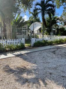 a white picket fence in front of a house at Ne Miami Cottage in Miami