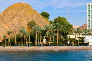 Elle offre une vue sur une plage bordée de palmiers et une montagne. dans l'établissement Steigenberger Hotel & Nelson Village, Taba, à Taba