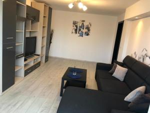 a living room with a black couch and a table at Apartament modern Târgoviște în regim hotelier in Târgovişte
