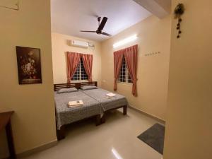 um quarto com uma cama e duas janelas em Gloria Homestay em Cochin