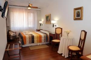 een slaapkamer met een bed, een tafel en stoelen bij Florida Hotel & Spa in Villa Carlos Paz