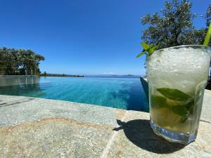 a drink sitting on a table next to a swimming pool at The Infinity 180 Luxury Suites in Milia