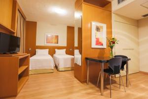 a hotel room with a bed and a desk and a tv at Nobile Suítes Uberlândia in Uberlândia