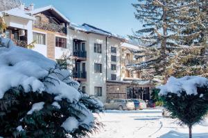 a snow covered tree in front of a building at Ostrova Holiday Village in Beli Osŭm