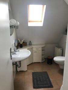 ein Bad mit einem Waschbecken, einem WC und einem Fenster in der Unterkunft Ferienwohnung Willi II in Spremberg