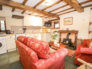 ein Wohnzimmer mit zwei roten Sofas und einem Kamin in der Unterkunft Stable End Cottage in Nether Wasdale