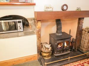 a stove in a living room next to a microwave at Stable End Cottage in Nether Wasdale