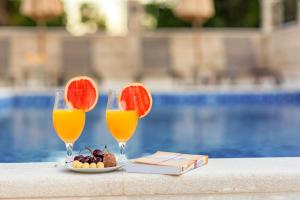 two glasses of orange juice and a plate of fruit at Luxury Apartments Queen in Petrovac na Moru
