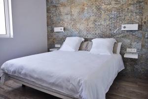 sypialnia z białym łóżkiem z ceglaną ścianą w obiekcie Design Vivienda V El Burgao by the Sea w Costa Teguise +25 zdjęć
