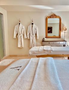 Le Vallon de Valrugues & Spa في سان ريمي دو بروفنس: غرفة نوم مع أرواب معلقة على الحائط ومرآة