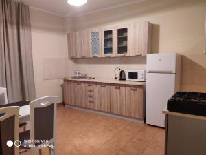 uma cozinha com armários de madeira e um frigorífico branco em Apartments Domovik "Uyut" em Mukachevo