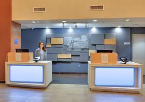 a woman standing behind two counters in a lobby at Holiday Inn Express & Suites - Austin - Round Rock, an IHG Hotel in Round Rock