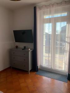 Zimmer mit einem TV und einer Kommode mit einem Fenster in der Unterkunft CHAMBRE D'HOTE in Gignac
