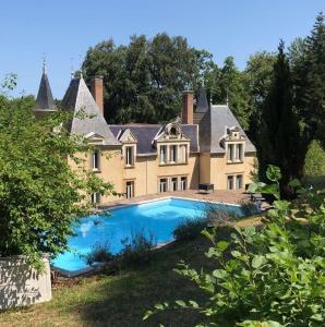 une grande maison avec une piscine en face de celle-ci dans l'établissement Chateau de Bonnevaux, à Villeneuve-de-Marc