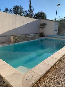 einem Pool mit blauem Wasser vor einem Gebäude in der Unterkunft CHAMBRE D'HOTE in Gignac