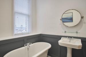 a bathroom with a sink and a tub and a mirror at Host & Stay - Huntcliff View Apartment in Saltburn-by-the-Sea