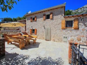 a stone house with a wooden table and an umbrella at Lovely Holiday Home in Starigrad with Private Swimming Pool in Starigrad-Paklenica