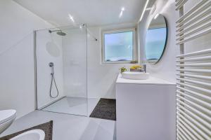 La salle de bains blanche est pourvue d'une douche et d'un lavabo. dans l'établissement Traumwohnung im Herzen Kalterns mit Panoramablick und Garage, à Caldaro