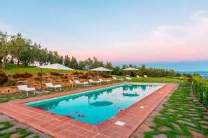 uma grande piscina com cadeiras e guarda-sóis em Villa Armonia Toscana - Homelike Villas em Massa e Cozzile
